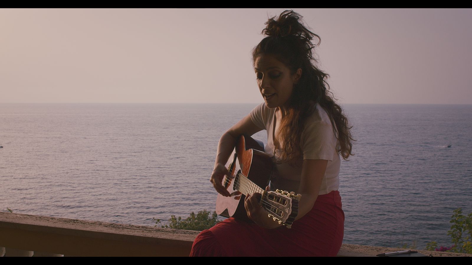 Alessia suona la chitarra davanti al mare