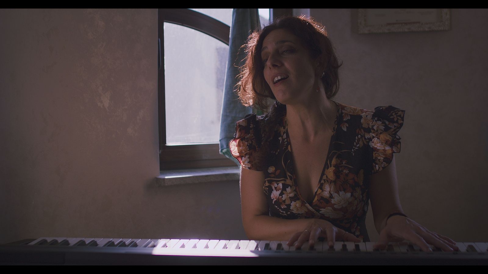 Alessia canta alla tastiera vicino alla finestra